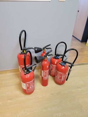 four fire extinguisors are lined up on a wooden floor