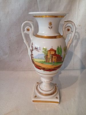un vase blanc avec un tableau posé sur une table
