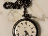 a silver pocket watch with a chain on a marble table