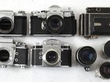 Plusieurs anciens appareils photo sont alignés les uns à côté des autres sur une surface blanche
