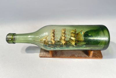 une bouteille en verre contenant un bateau, posée sur un socle en bois