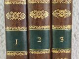 three old books are lined up in a row on a table