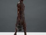a bronze statue of a woman holding a pot on top of a table