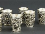 six verres à shot en argent posés les uns à côté des autres sur une table