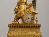 a gold clock sitting on top of a wooden table