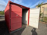 a red container sitting in the middle of a parking lot