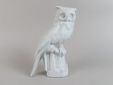 une figurine blanche représentant un hibou perché sur une souche d'arbre