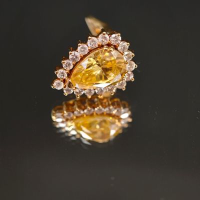 un gros plan d'une bague sertie d'un diamant jaune et blanc posée sur une surface réfléchissante