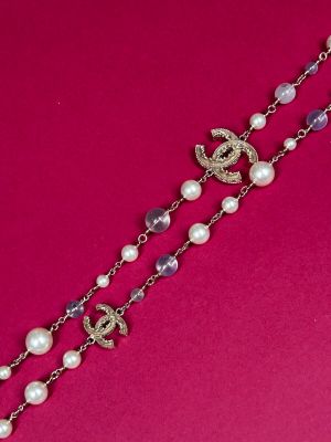 a close up of a necklace on a pink surface