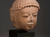 head of a buddha statue on a black stand against a gray background