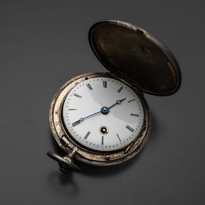 une montre de poche en argent posée sur une table