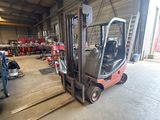 a forklift in a warehouse with other vehicles in the background