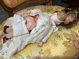 a doll that is laying on a chair with a teddy bear