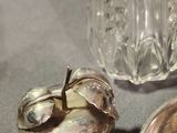 a silver plate with an apple on it next to a glass vase