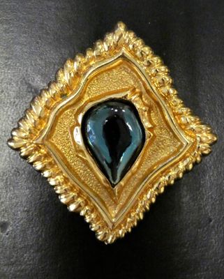 an image of a gold and blue broochle on a black surface