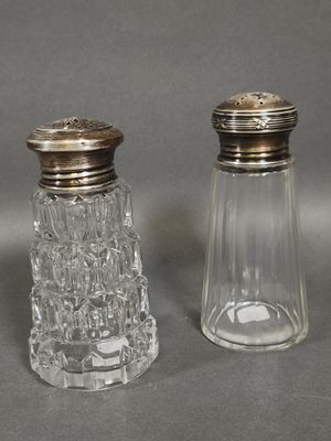 two glass salt and pepper shakers with silver tops on a gray surface