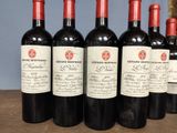 six bottles of red wine are lined up on a wooden table