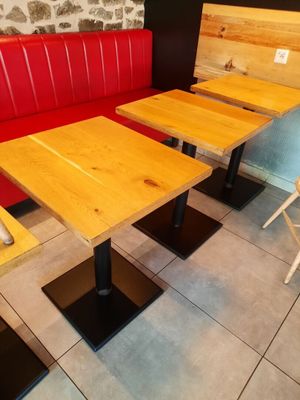 tables and benches in a restaurant with a stone wall behind them