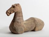une petite statue représentant un cheval assis sur une surface blanche