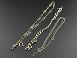 a group of three silver necklaces on a black surface