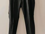 un pantalon en cuir noir suspendu à un cintre devant un mur blanc