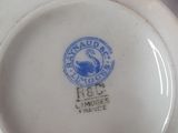 a white plate with a blue seal on it next to a bowl of oranges