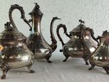 three silver teapots and a coffee pot on a table
