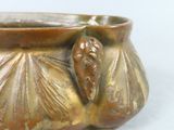a close up of a bronze vase with a bird on it