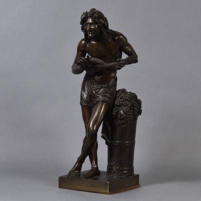 a bronze statue of a man with a basket of grapes