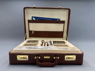 un coffret marron contenant de l'argenterie, posé sur une surface grise