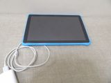 une tablette bleue posée sur une table à côté d'un chargeur