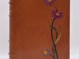 un carnet en cuir marron orné de fleurs violettes et d'un papillon