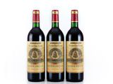 three bottles of red wine sitting next to each other on a white surface