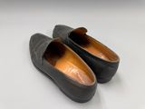 une paire de chaussures en cuir noir posée sur une surface blanche