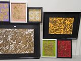 quatre tableaux encadrés, de couleurs et de motifs variés, accrochés au mur