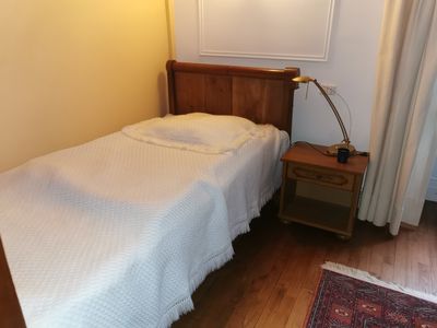 un petit lit dans une petite chambre, avec une tête de lit en bois