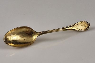a gold spoon on a white surface with a spoon in the middle
