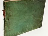 an old green book sitting on top of a white surface