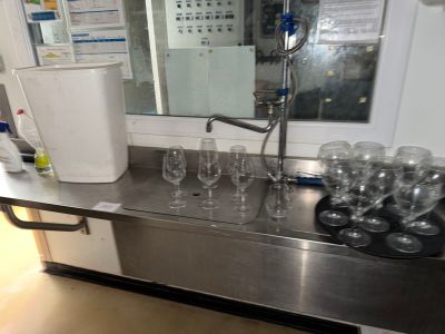 bottles and glasses are lined up on a stainless steel counter