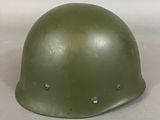 an army green helmet sitting on top of a white surface