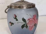 a blue vase with a rose on it on a table