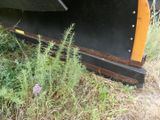 a snow plow that is sitting in the grass