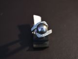a ring with a black pearl on it on a black surface