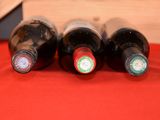 three bottles of wine are lined up on a red cloth