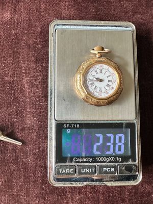 une montre de poche posée sur une balance, à côté d'un trousseau de clés