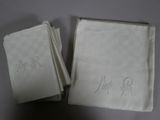 two white napkins with monograms on them sitting on a table