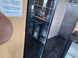 a person that is pointing at a refrigerator in a kitchen