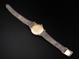 a gold watch on a black surface with a black background