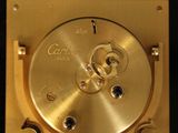 a gold clock that is sitting on a black surface