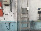 une échelle appuyée contre un mur, à côté d'une borne d'incendie